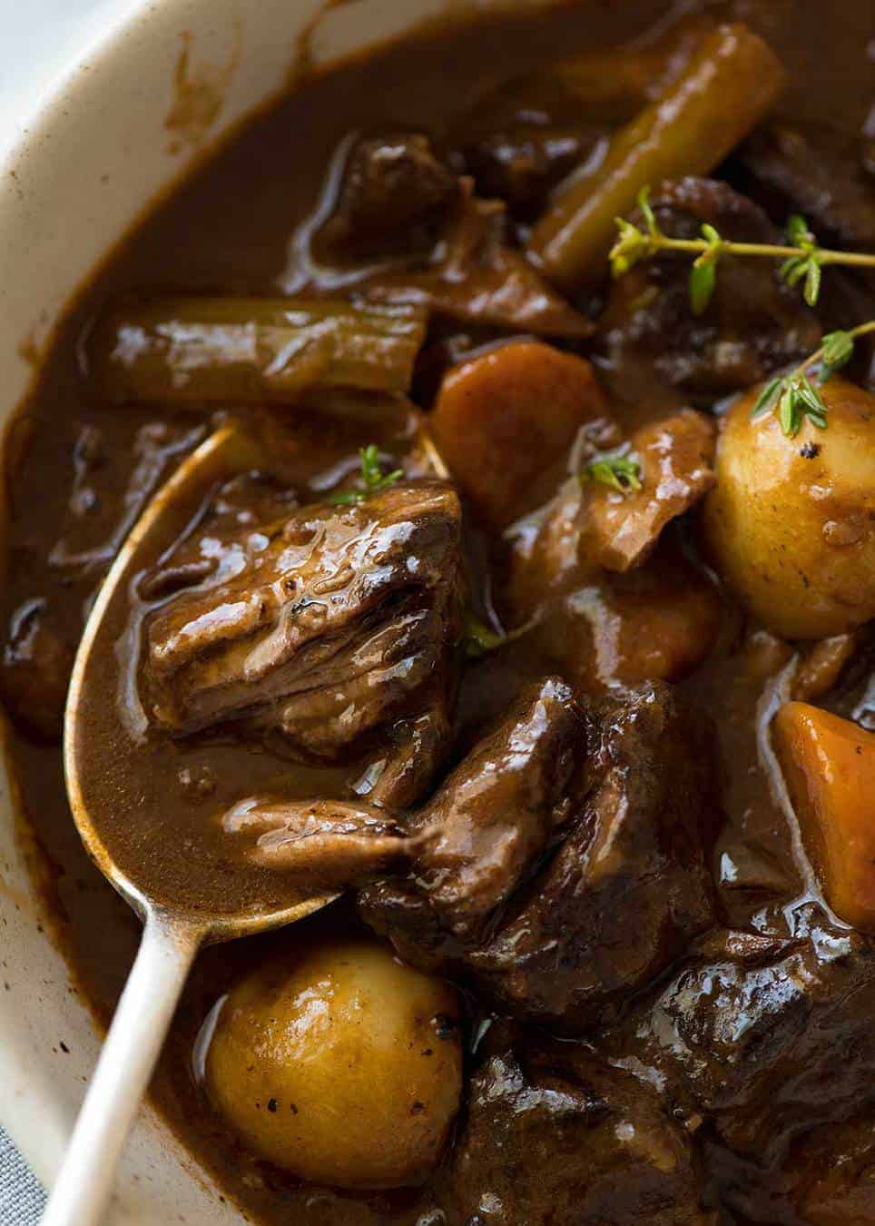 Close up of Beef Stew with a piece of beef in a spoon, partially falling apart.