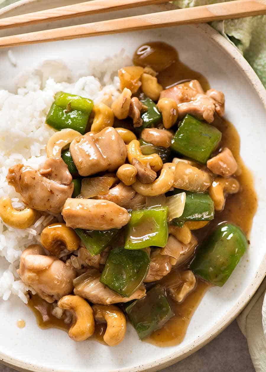 Chinese Cashew Chicken served on rice in a white bowl with chopsticks, ready to be eaten