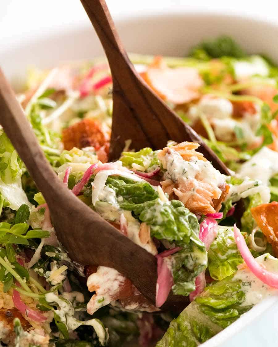 Close up of salad servers picking up Celebration Salmon Salad (salad main dish with salmon)