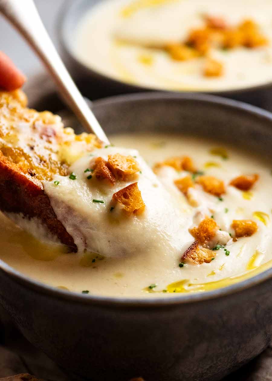 Close up of crusty bread being dunked into Celeriac Soup