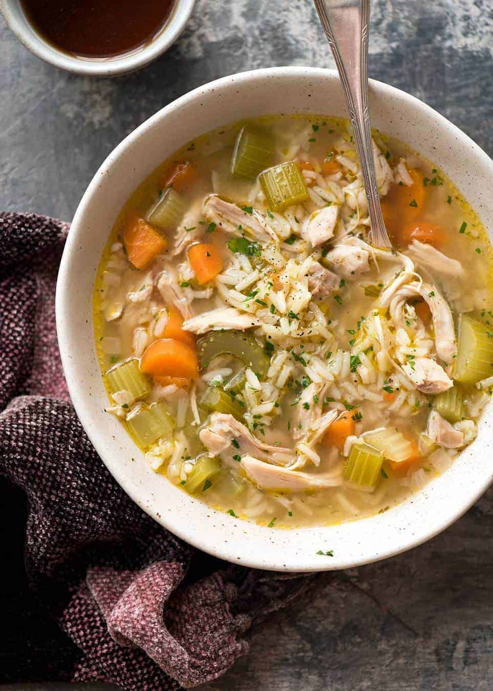 Overhead photo of easy chicken and rice soup in a rustic beige bowl, ready to be eaten.