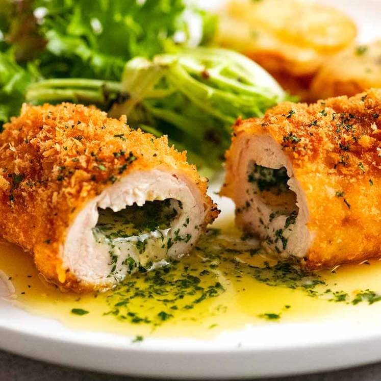 Cut open piece of Chicken Kiev on a plate, ready to be eaten