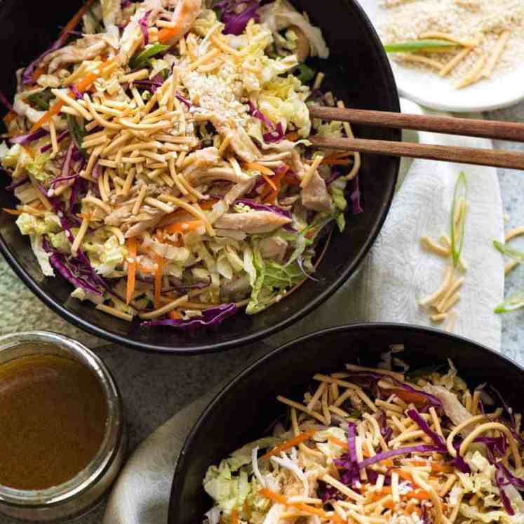 Overhead photo of 2 black bowls with Chinese Chicken Salad with Asian Dressing, ready to be eaten