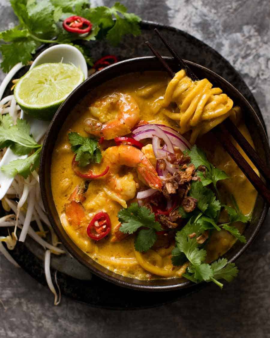 Overhead photo of Thai Coconut Soup with Shrimp/Prawns and Noodles in a black bowl, ready to be eaten