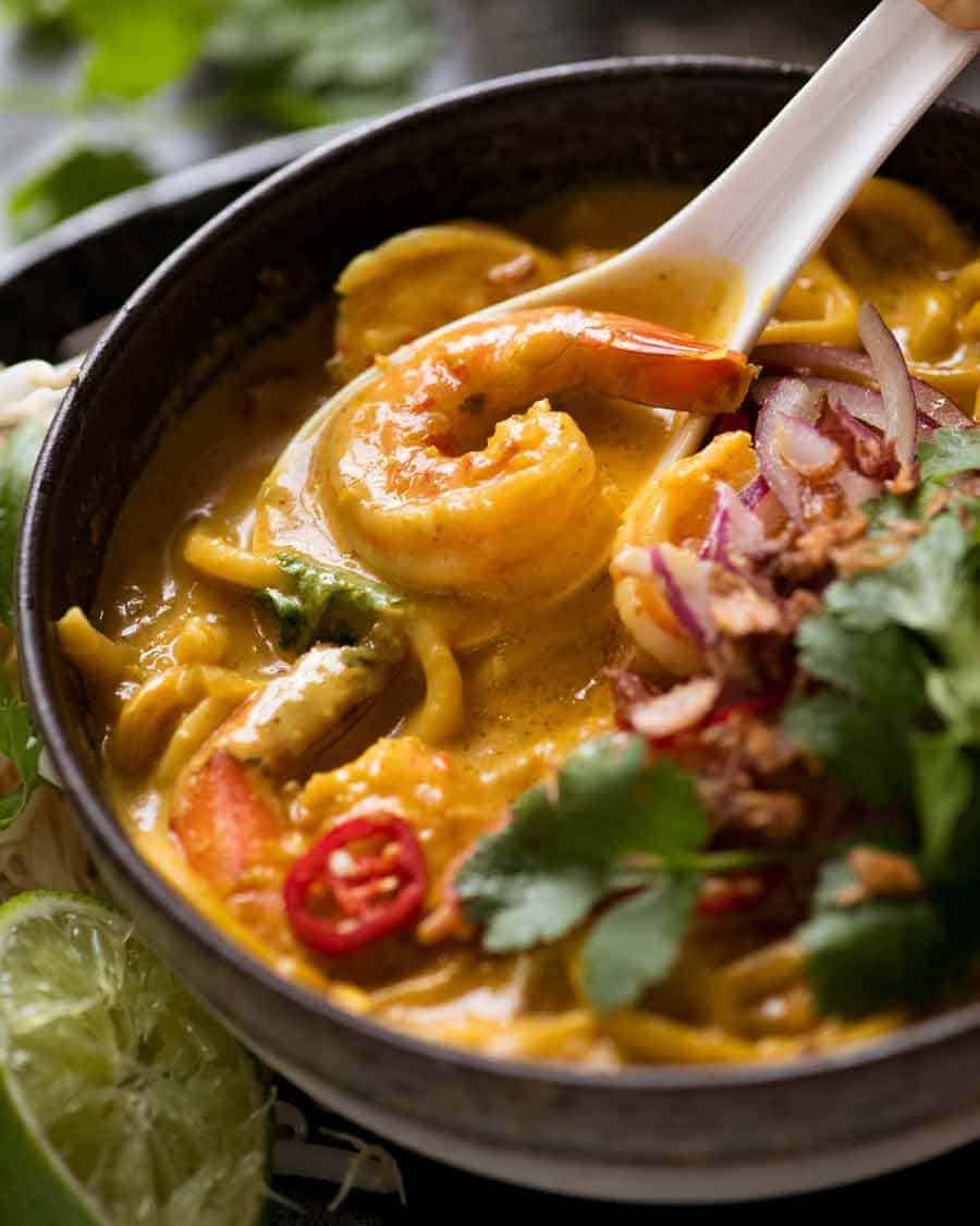 Close up of spoon scooping up Thai Coconut Soup with Shrimp/Prawns and Noodles