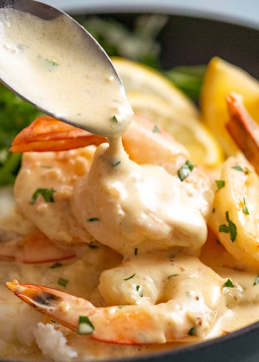 Spooning Creamy Garlic Sauce over prawns