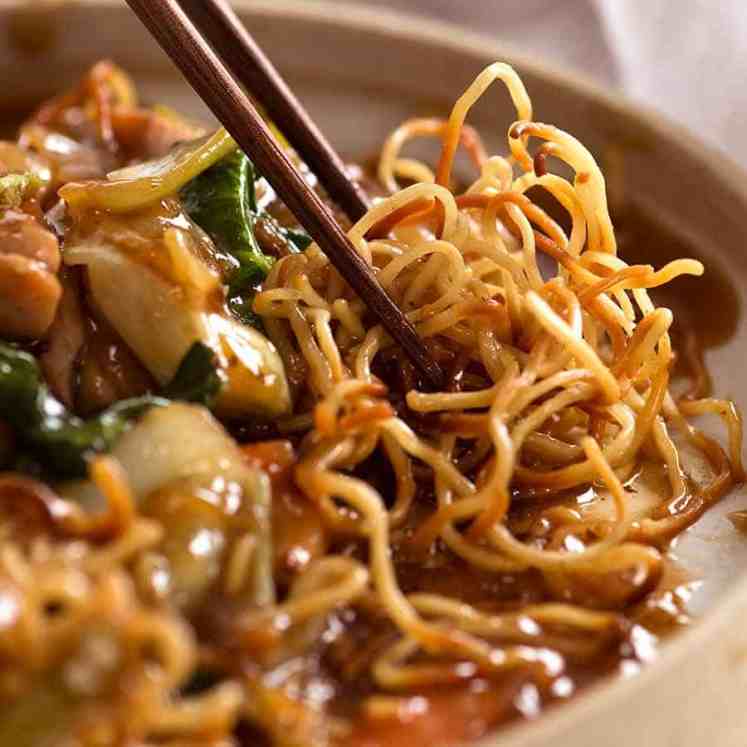 Close up photo of chopsticks picking up Chinese Crispy Noodles (Chow Mein)