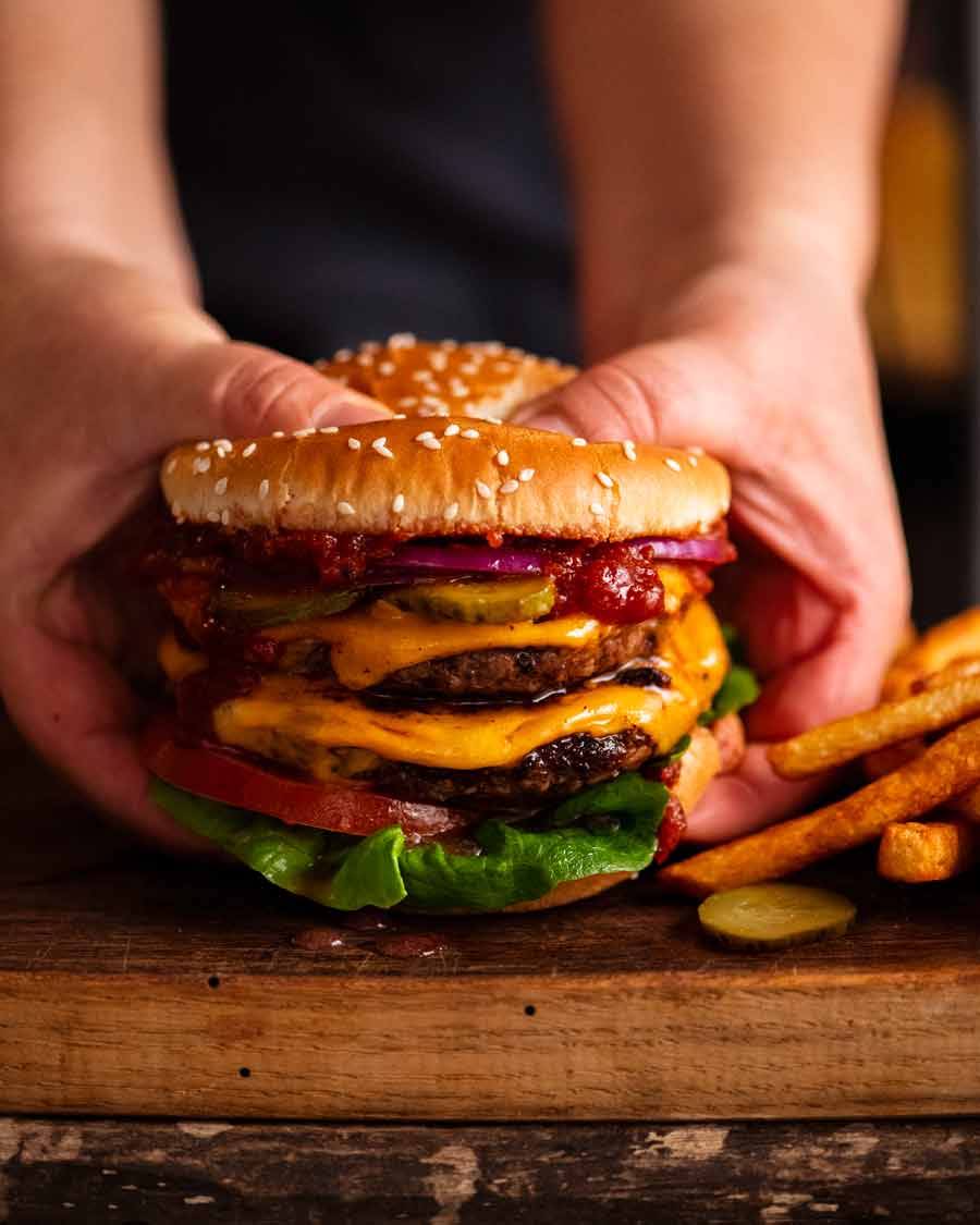 Hand holding double cheeseburger