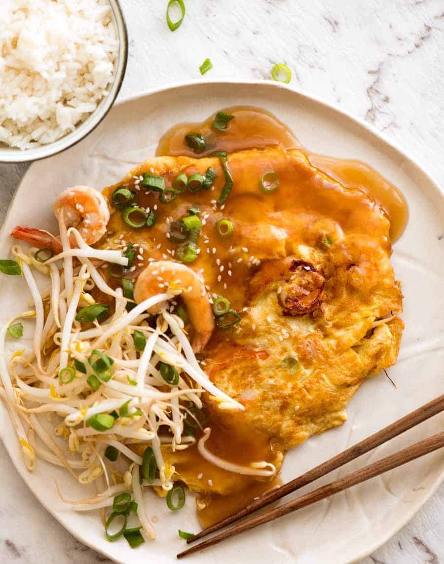 Overhead photo of Egg Foo Young on a rustic white plate with a side of rice, ready to be eaten