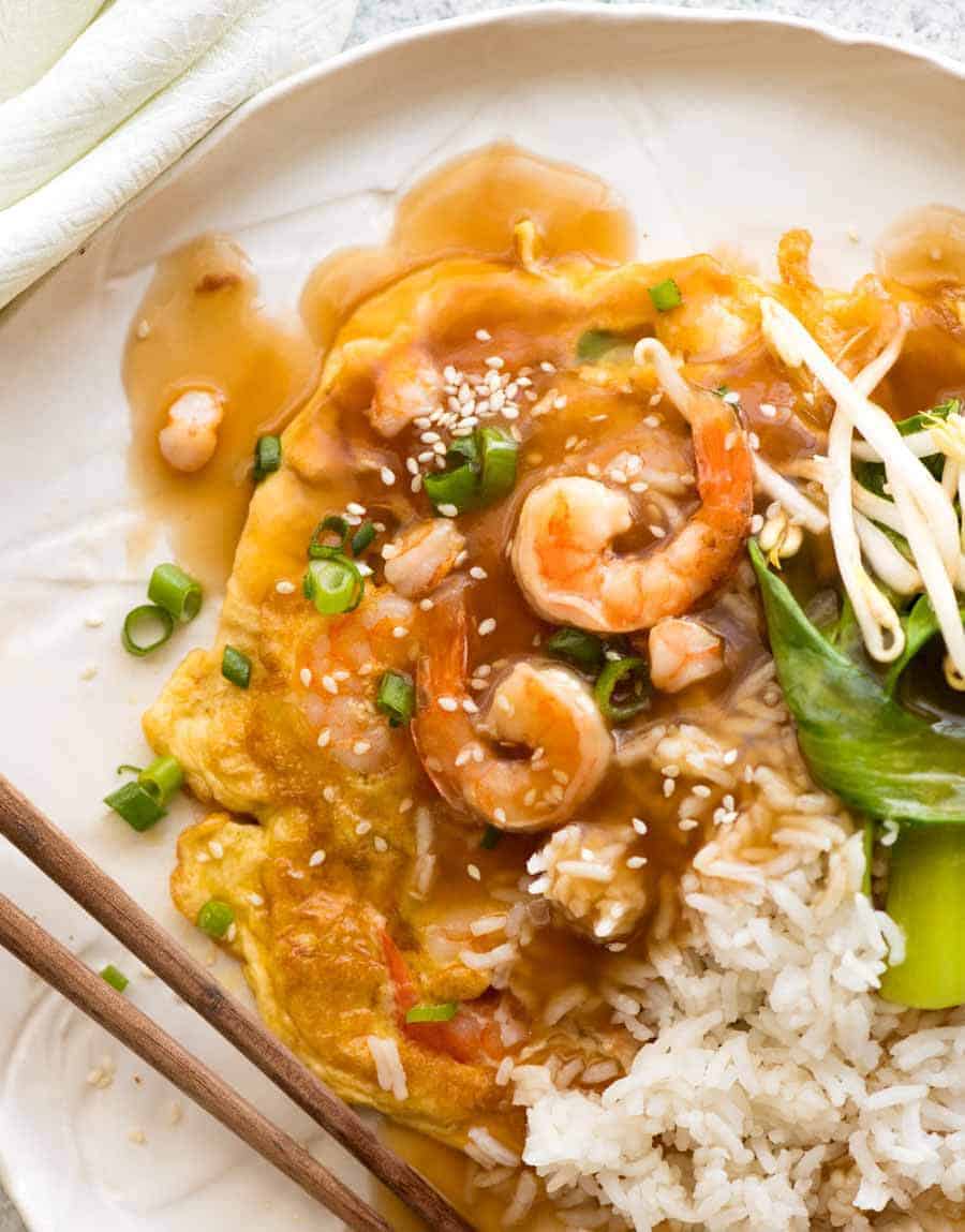 Overhead photo of Egg Foo Young on a white plate with a side of steamed bun choy and rice, ready to be eaten