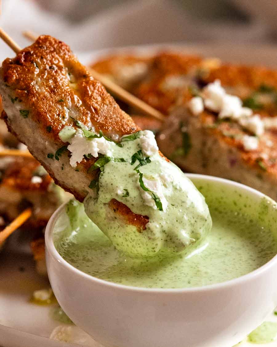 Dipping fish koftas into mint yogurt sauce