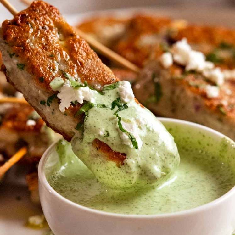 Dipping fish koftas into mint yogurt sauce