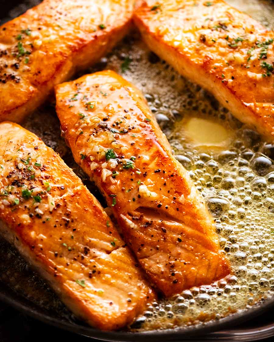 Garlic Butter Salmon in a skillet surrounded by foaming garlic butter