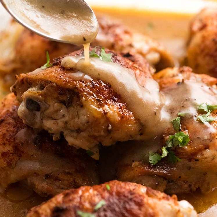 Spoon drizzling gravy over Crispy Baked Chicken in gravy