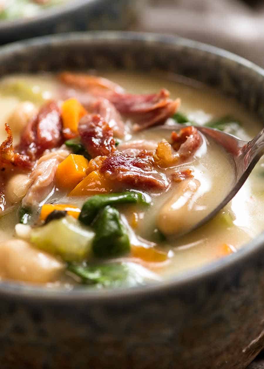 Close up of spoon dipping into bowl of Slow Cooker Ham Bone Soup with Beans