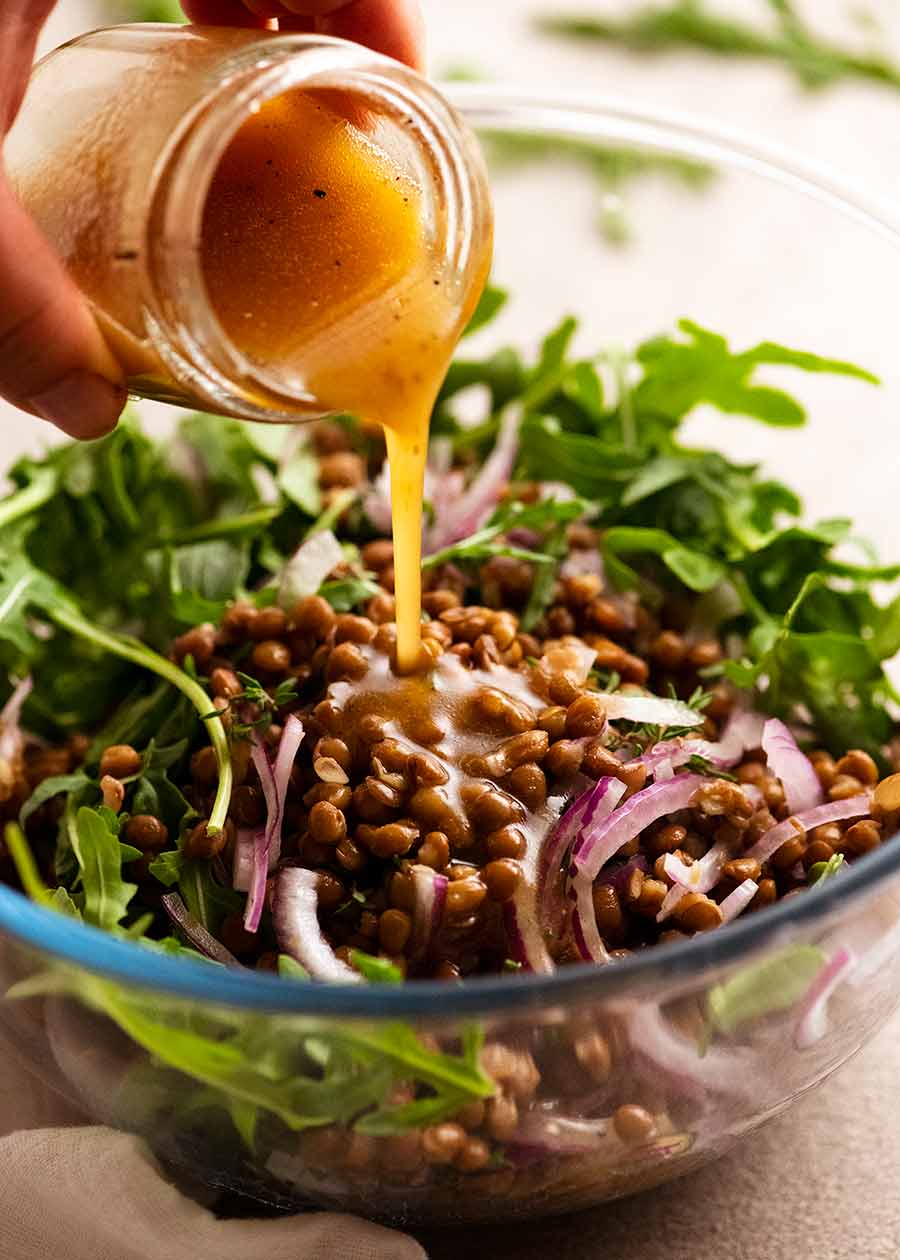 Pouring dressing over Honey Cinnamon Pumpkin Lentil Salad