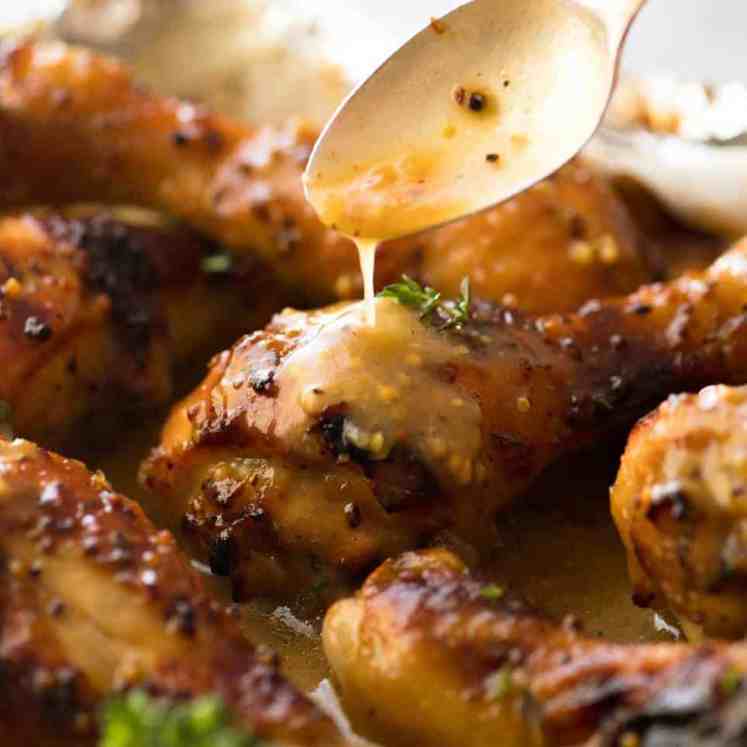 Close up of Honey Mustard sauce being drizzled over Baked Chicken Drumsticks