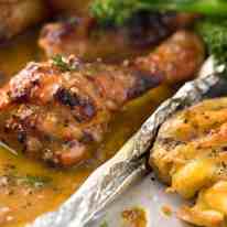 Close up of sticky Honey Mustard Chicken Drumsticks and crispy smashed potatoes, fresh out of the oven.