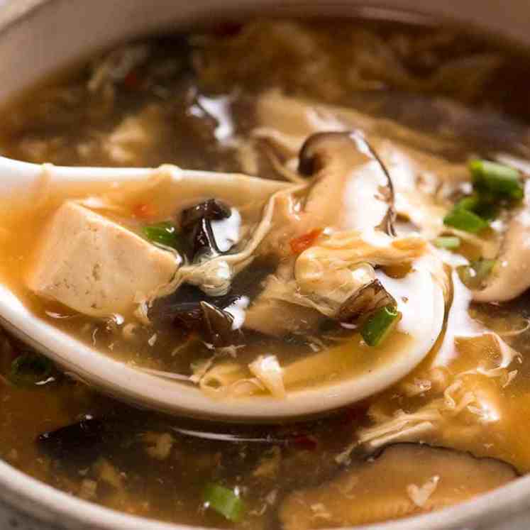 Close up of Chinese spoon scooping up Hot and Sour Soup from bowl