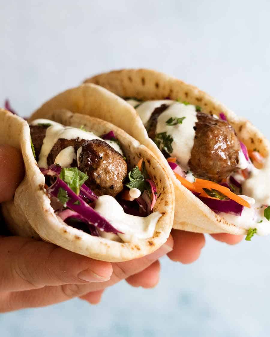 Hand holding Lamb Koftas stuffed I pita bread