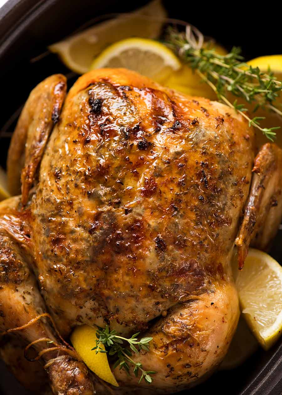 Overhead photo of Slow Cooker Roast Chicken (whole chicken) on a serving platter with lemon wedges and thyme, ready to be served