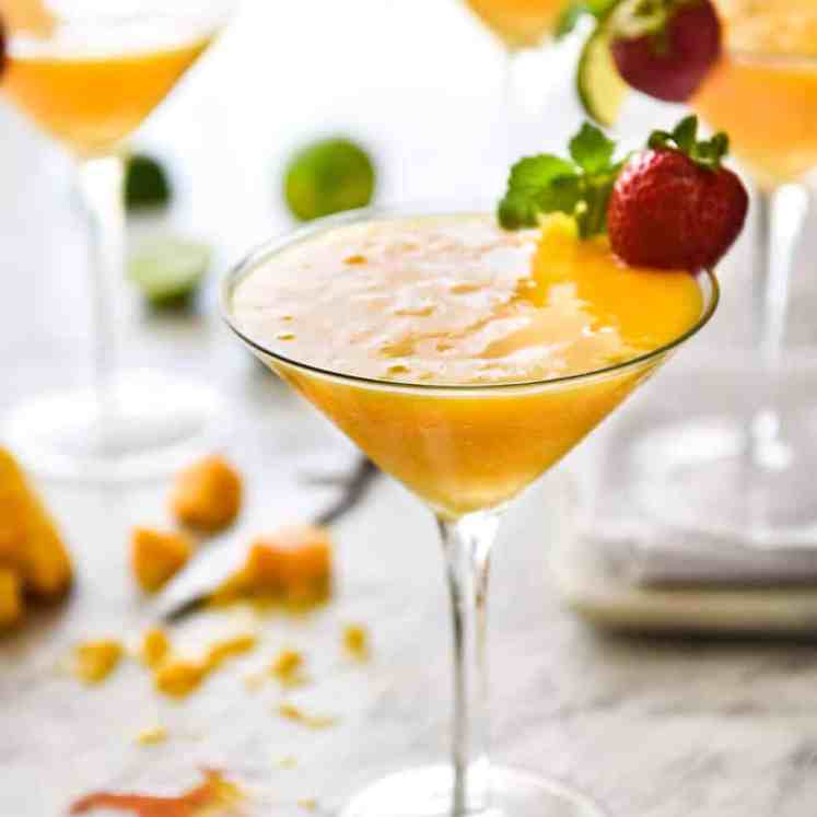 Frozen Mango Daquiris in cocktail glasses, garnished with strawberries.