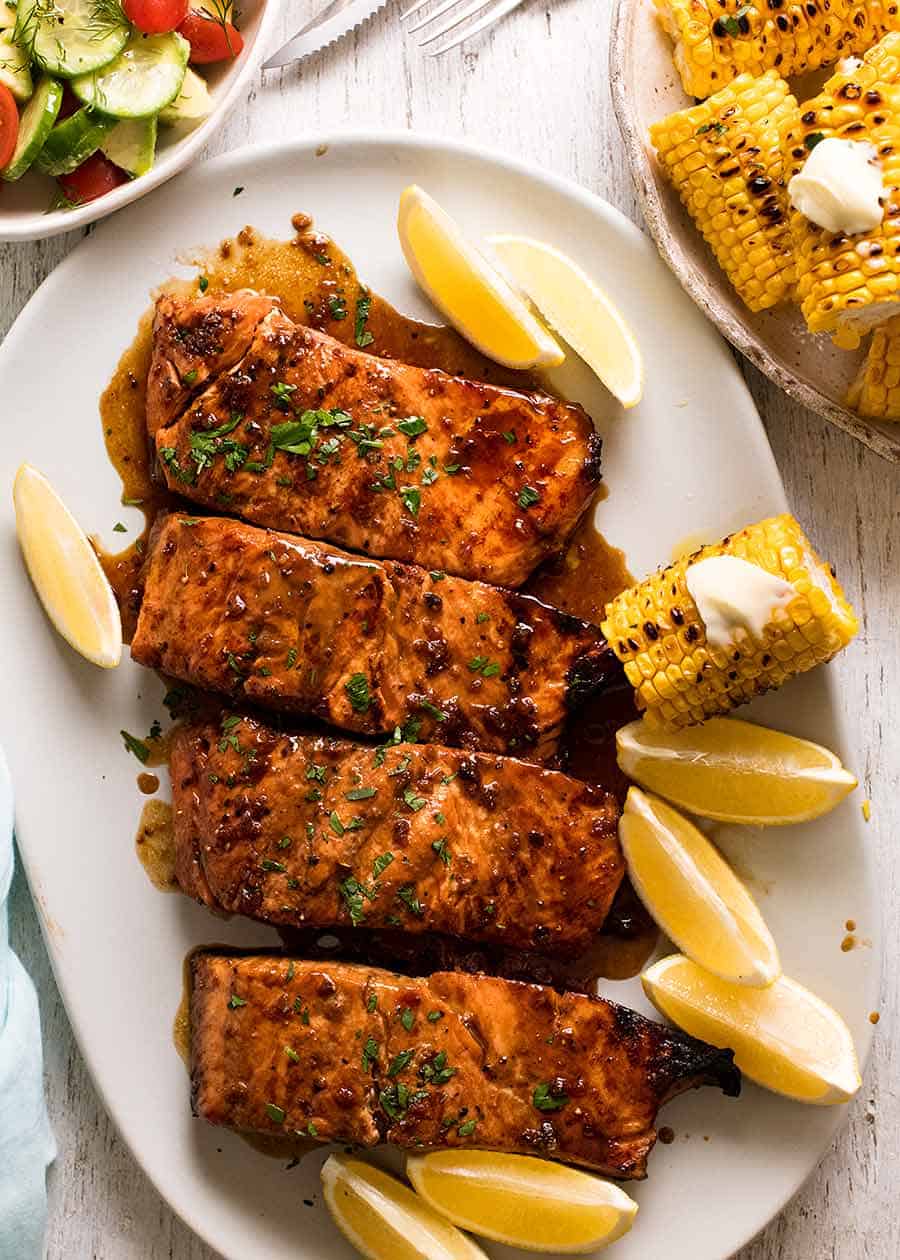 Overhead photo of Marinated Grilled Salmon dinner with a side of cucumber avocado tomato salad and grilled corn