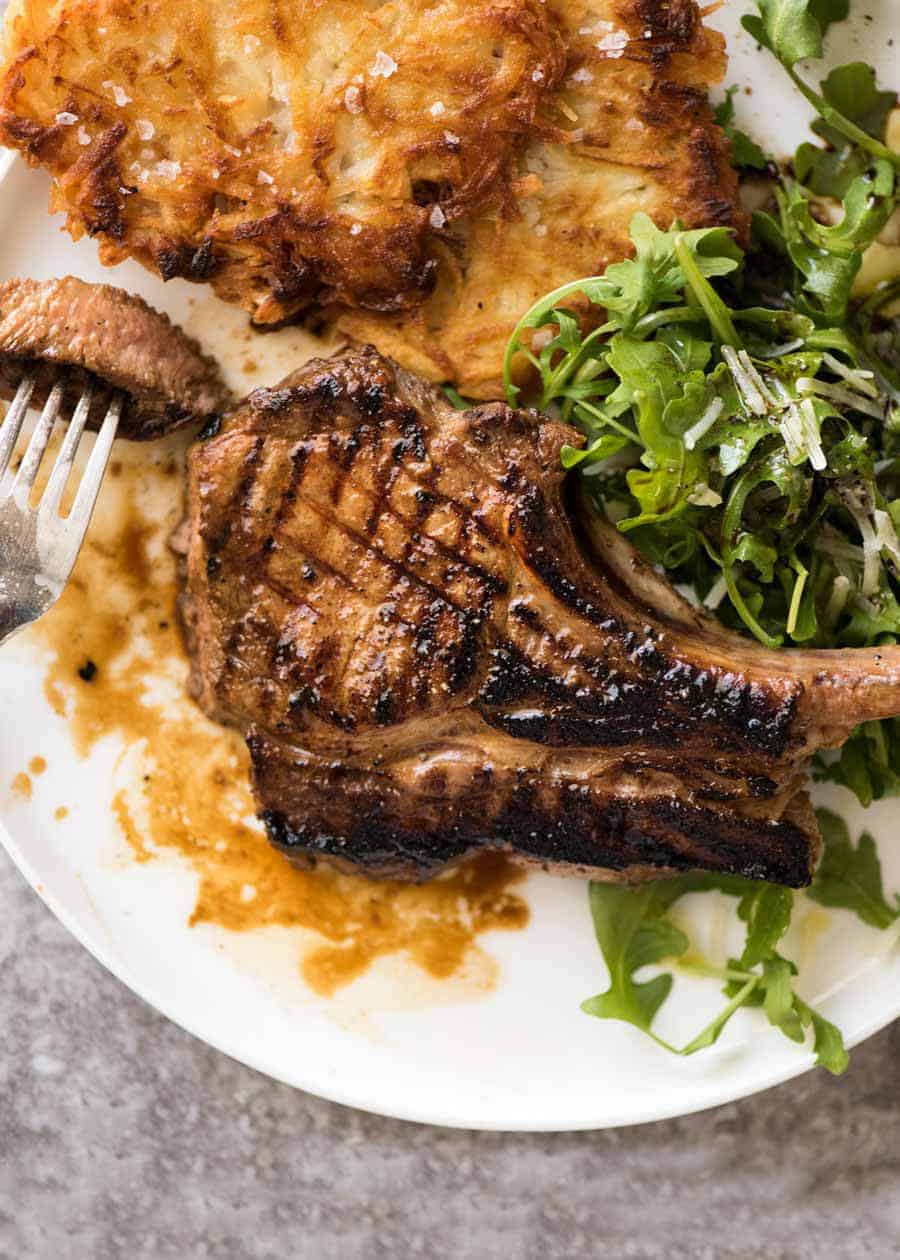 Overhead photo of Grilled chops on a plate with potato rosti and salad, made using amade using a great Pork Chop Marinade