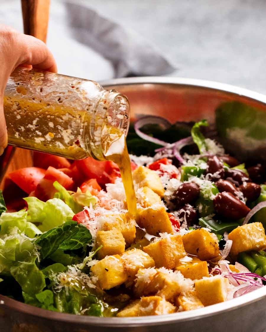 Pouring Italian Dressing over Mega Italian Salad