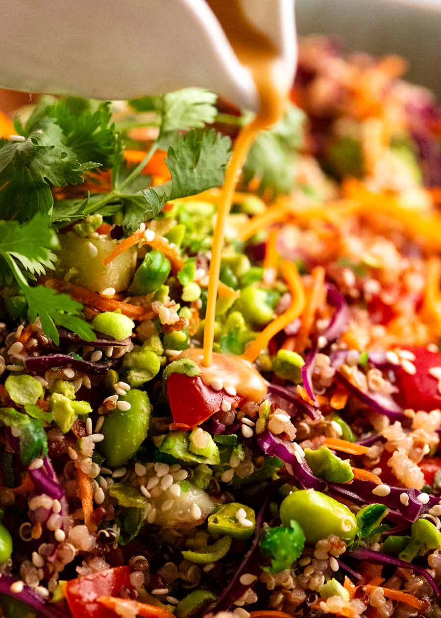 Close up of pouring garlic ginger dressing over Quinoa Salad