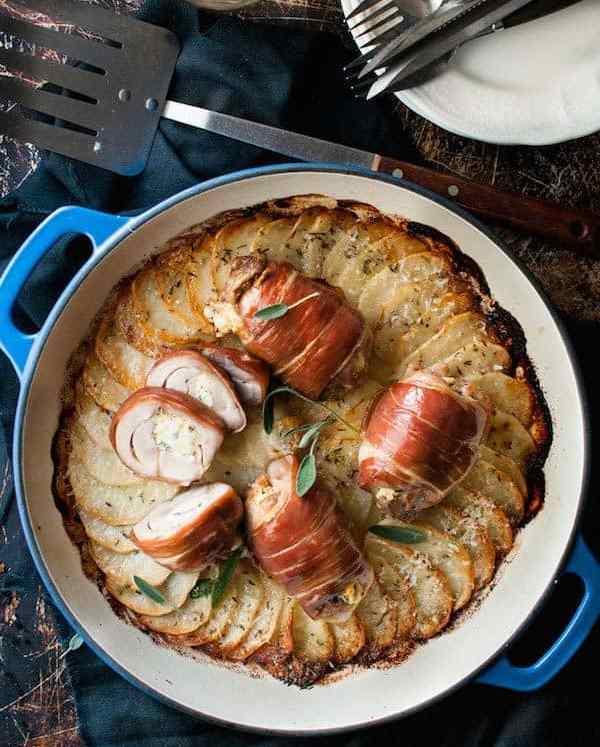 Prosciutto Wrapped Chicken and Scalloped Potatoes in a round blue casserole pan