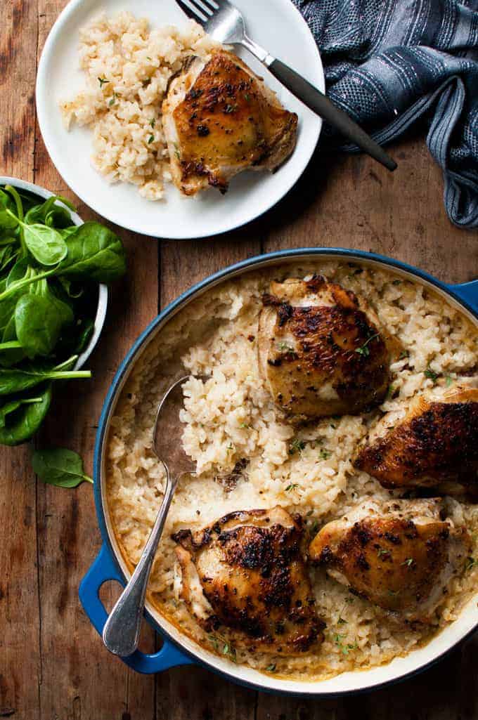 Overhead shot of a table with One Pot Creamy Baked Risotto with Lemon Pepper Chicken in pot and served on a plate