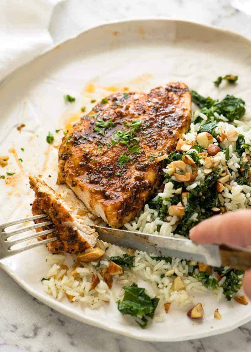 Juicy Oven Baked Chicken Breast on a white plate with a side of Garlic Butter Rice with Kale