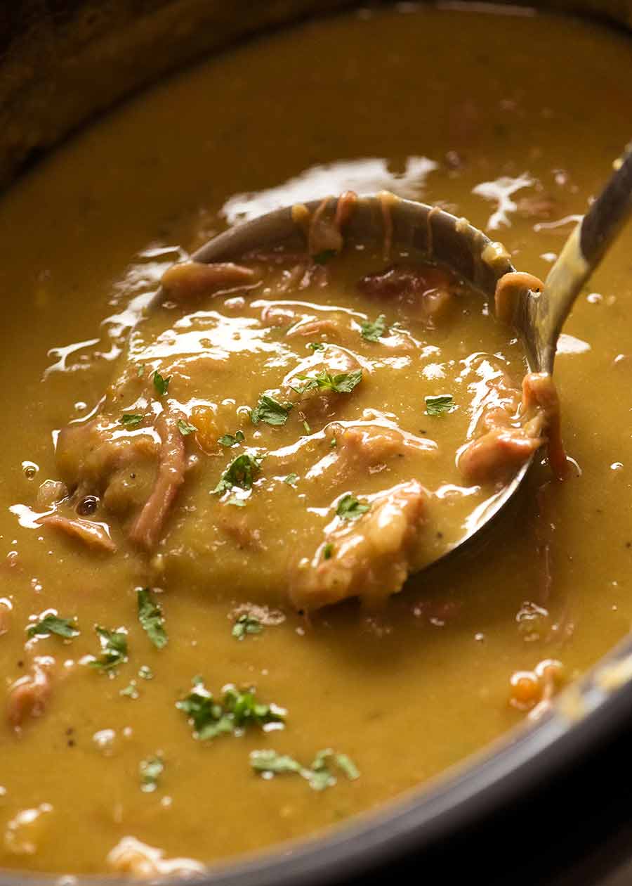 Close up of ladle scooping up Pea and Ham Soup from a slow cooker.