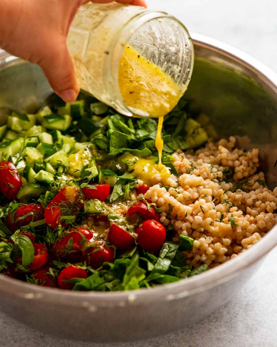 Driving lemon dressing over Pearl couscous salad