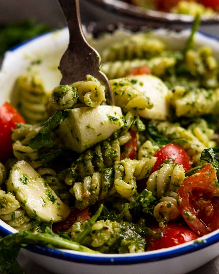 Close up of fork picking up Pesto pasta salad