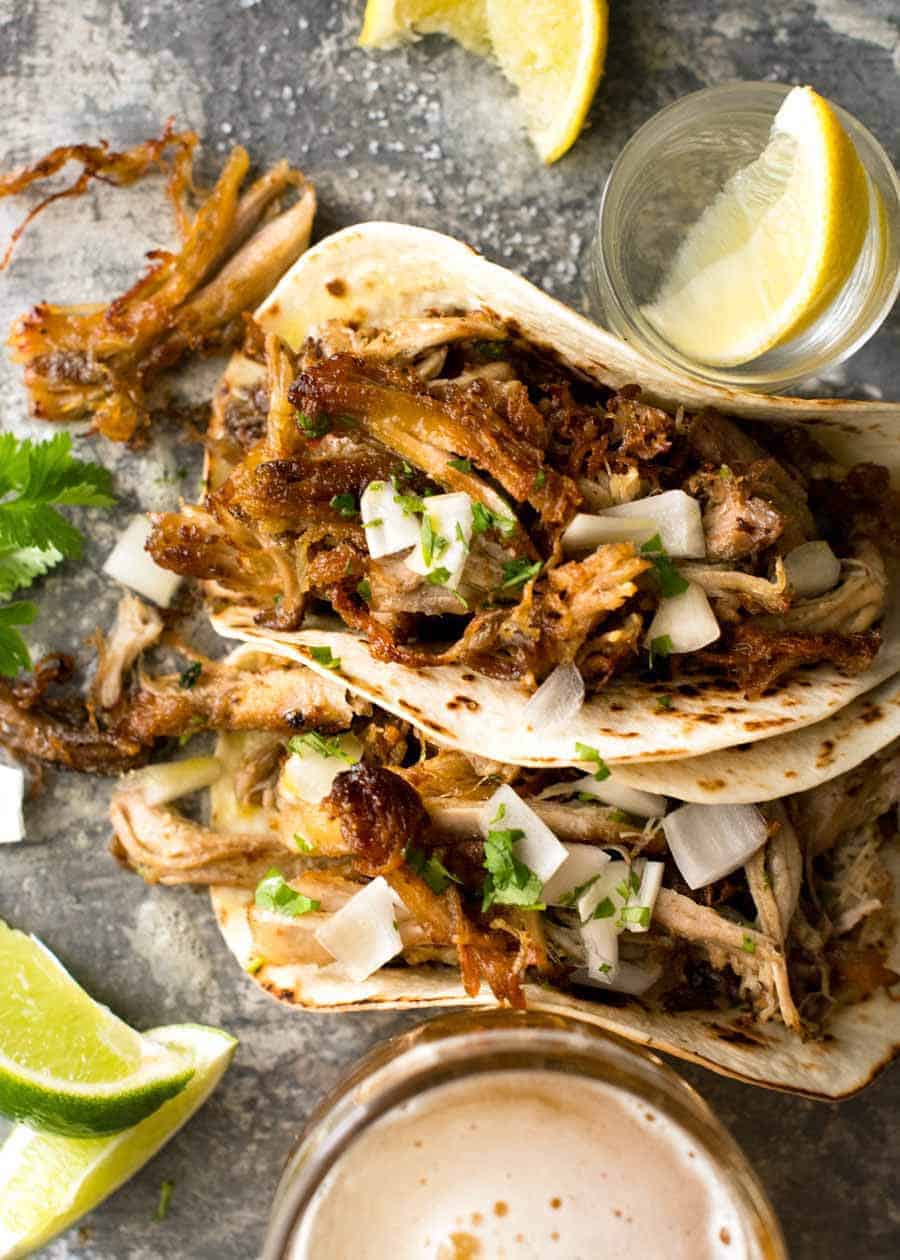 Overhead photo of two Pork Carnitas Tacos with tequila shots on the side.