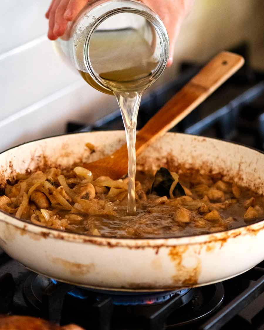 Pouring homemade chicken stock into pot for Chicken Fricasse