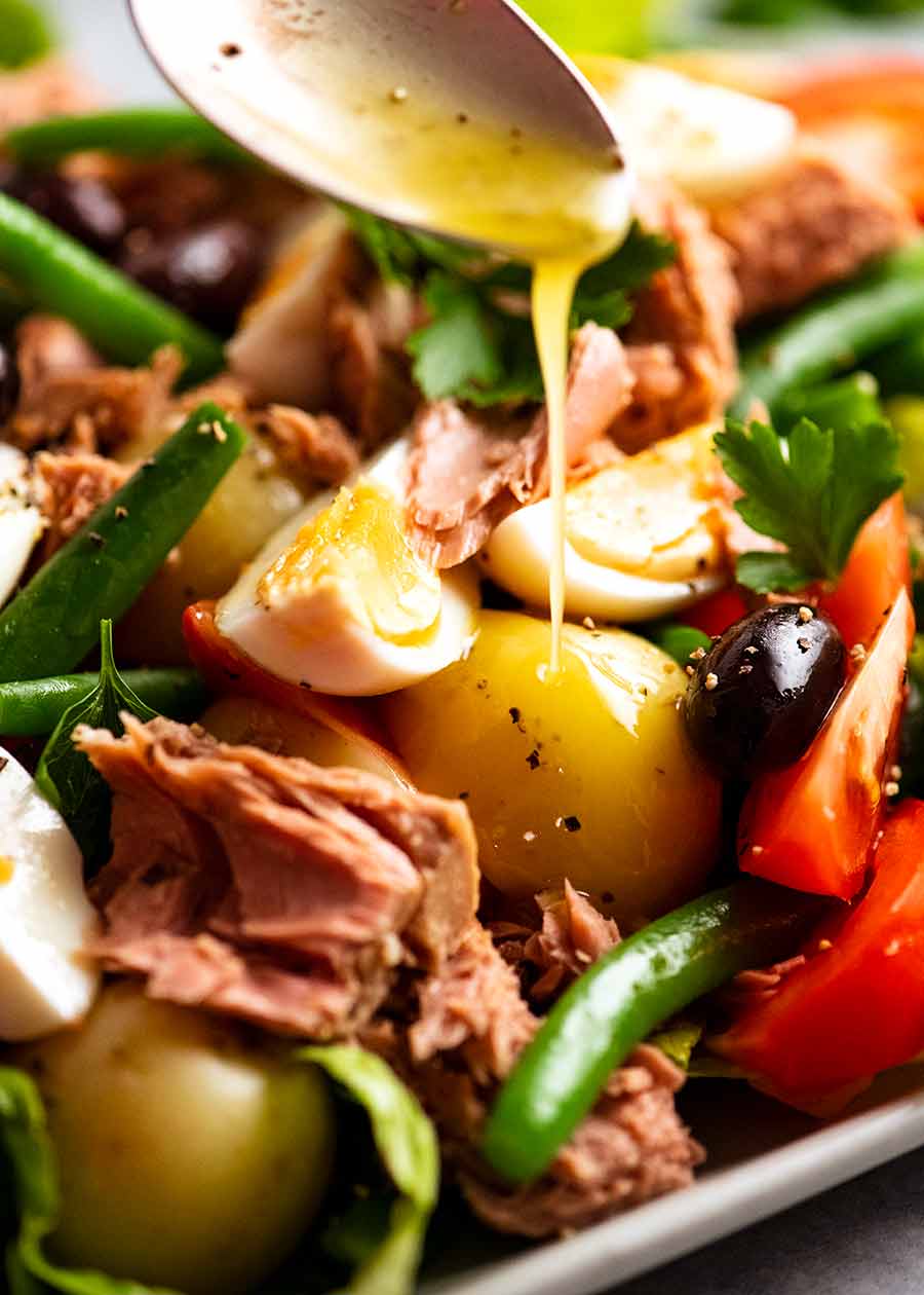 Drizzling lemon dressing over Salad Nicoise - French Tuna Salad