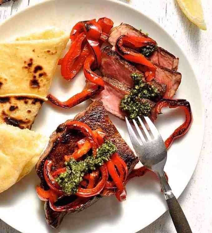 Steak with Pesto and chargrilled capsicum on a white plate, ready to be eaten.