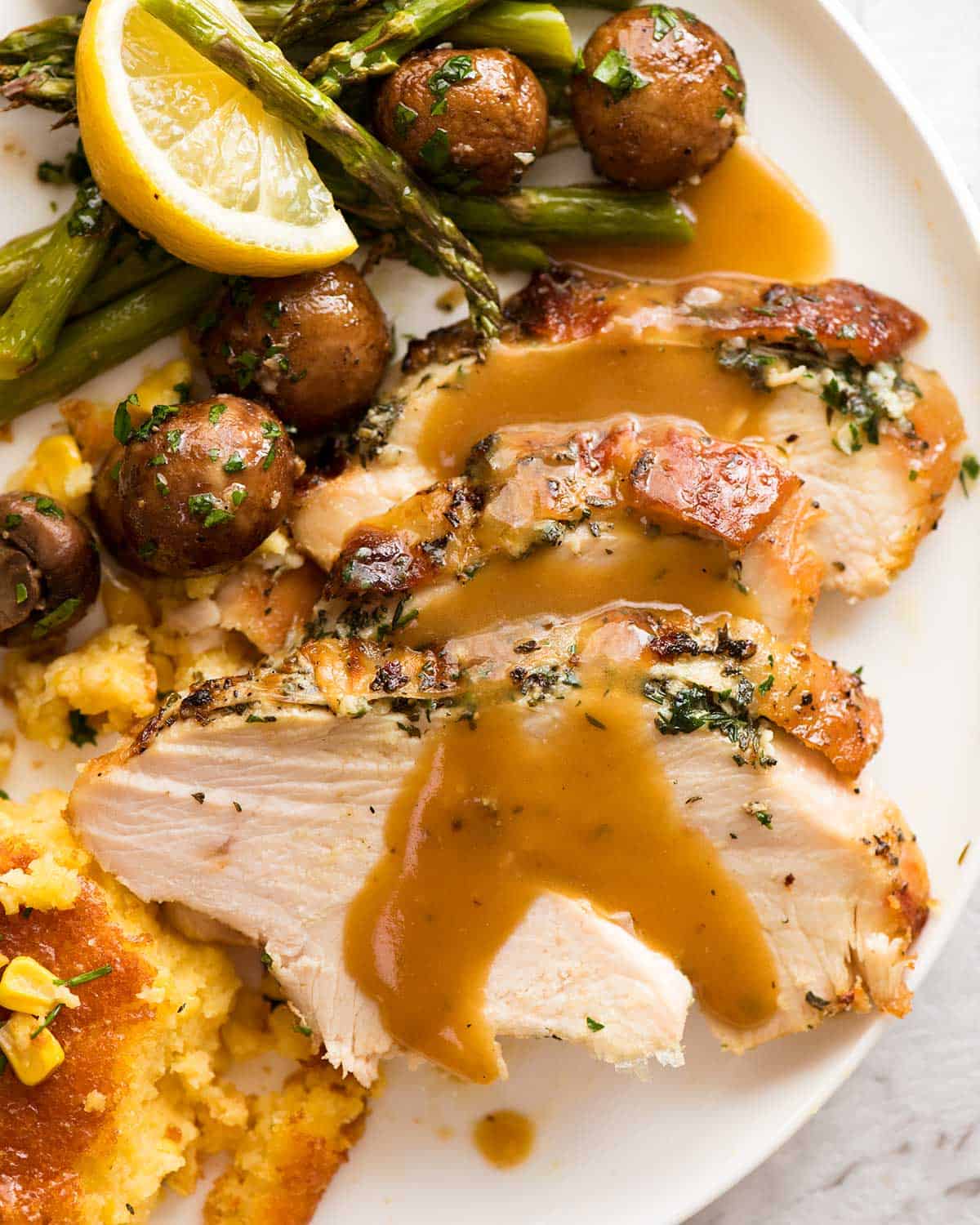 Garlic Herb Slow Cooker Turkey Breast dinner plate with creamy corn casserole, roasted mushrooms, and lemon garlic asparagus