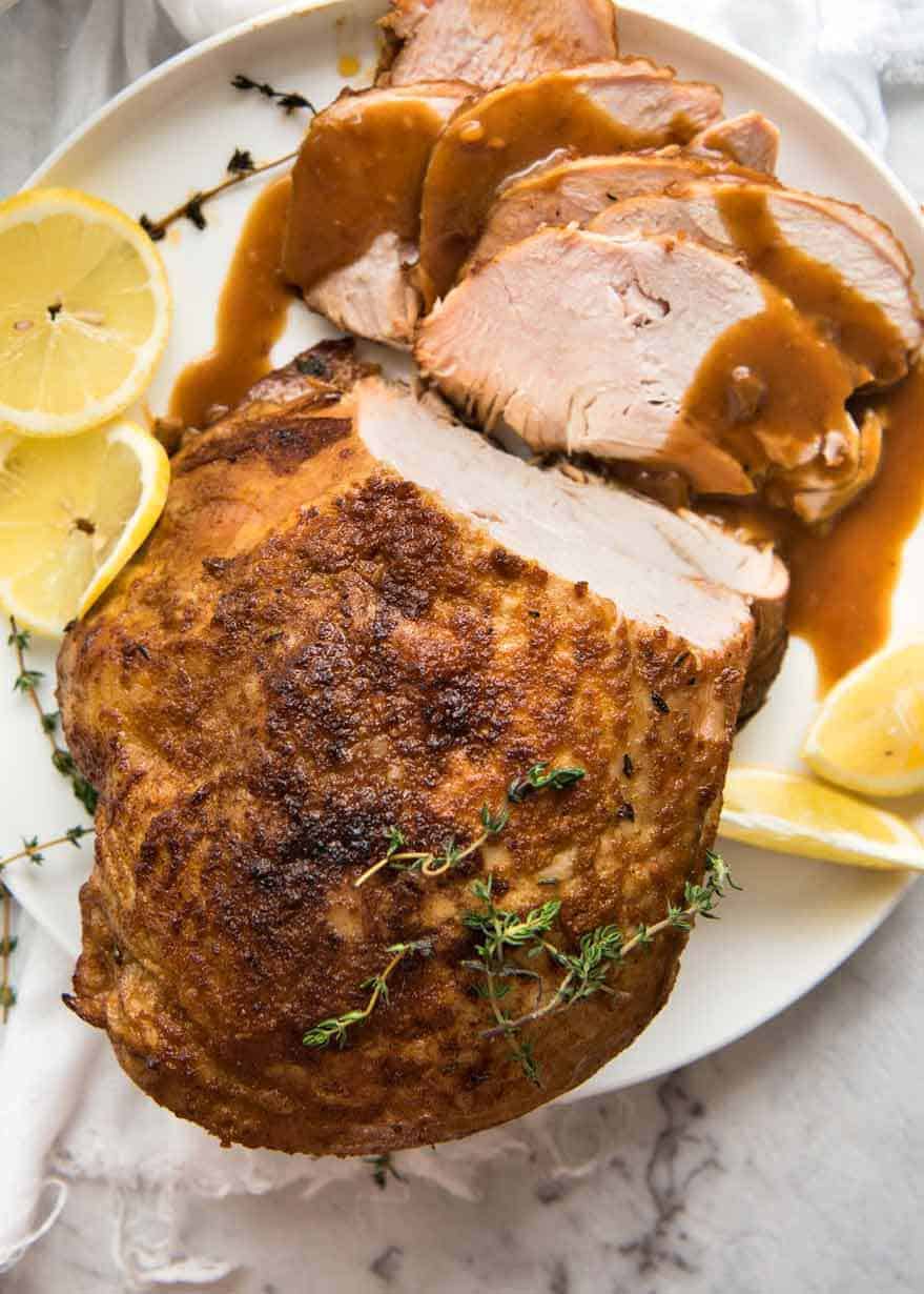 Overhead photo of Slow Cooker Turkey Breast on a white plate with some slices carved, drizzled with gravy