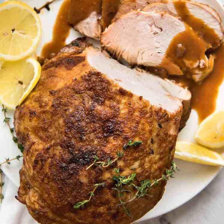 Overhead photo of Slow Cooker Turkey Breast on a white plate with some slices carved, drizzled with gravy