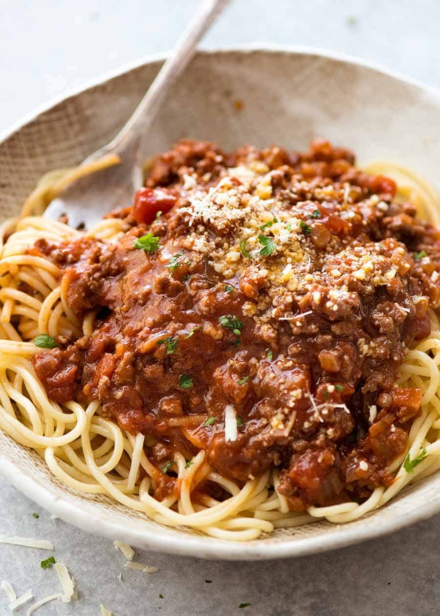 Spaghetti Bolgonese in a bowl sprinkled with fresh parmesan, ready to be eaten