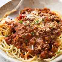 Spaghetti Bolgonese in a bowl sprinkled with fresh parmesan, ready to be eaten