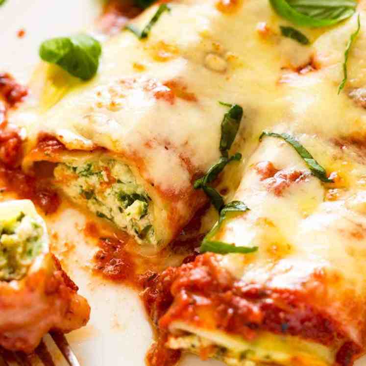 Close up photo of 2 pieces of Spinach and Ricotta Cannelloni with tomato pasta sauce on a plate