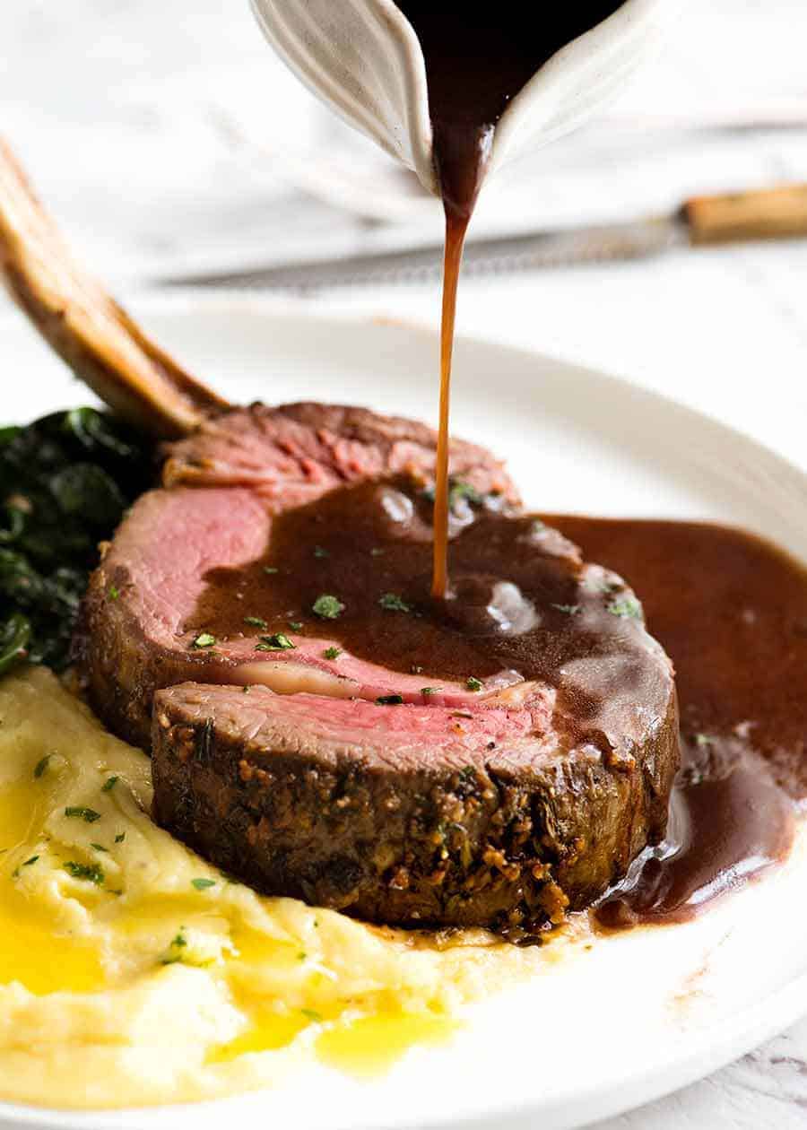 Red Wine Sauce being poured over Beef Standing Rib Roast (Prime Rib)