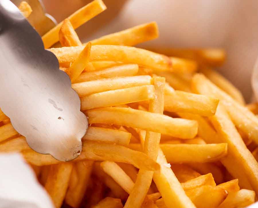 Tongs picking up homemade French fries