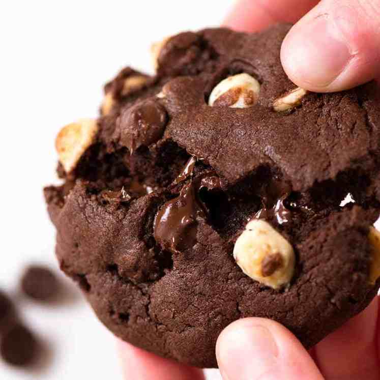 Close up of hand breaking a Better than Byron Bay Triple Chocolate Cookie. Chewy on the inside, 40% chocolate, with crispy edges.