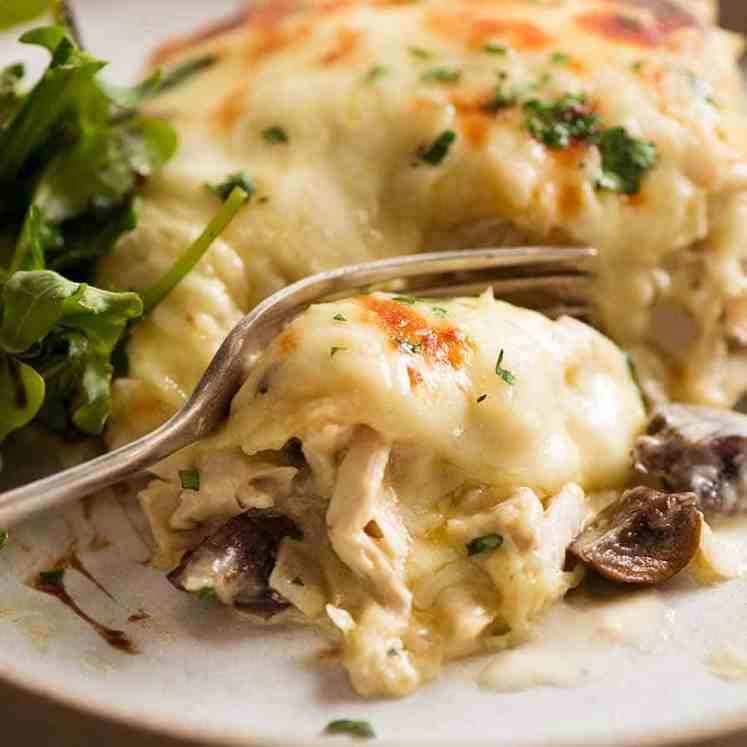 Close up of fork cutting into slice of Chicken Lasagna on a plate, ready to be eaten